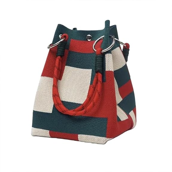 A small bucket-style handbag with a geometric patchwork pattern in red, dark teal, and off-white. It features thick red rope handles threaded through silver metal O-rings at the top, set against a plain white background.